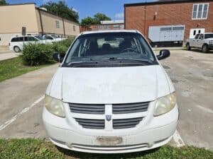 Front of White Dodge mini-van, missing plates and significant wear